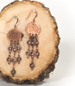 Copper dangle earrings on wood background