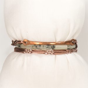 Copper and stone bracelet on fabric display.