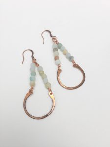 Beaded earrings with copper loops on white background.