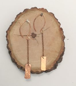 Copper earrings on tree trunk slab