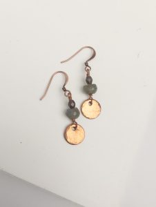 Copper and stone dangle earrings on white surface.