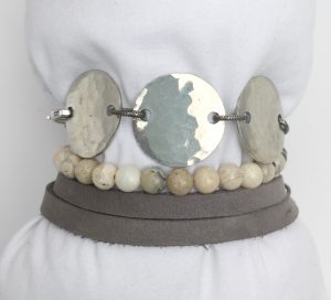 Beaded bracelet with silver discs on display stand.