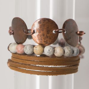 Copper and stone beaded bracelet on glass display.
