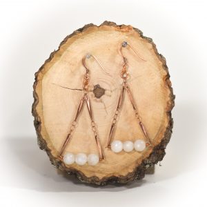 Handmade copper and stone earrings on wood slice.