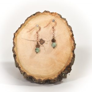 Handcrafted earrings displayed on wood slice