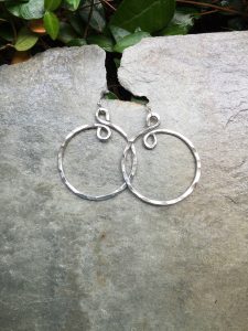 Silver hoop earrings on stone background