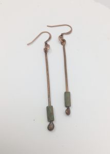 Copper earrings with green beads on white background.