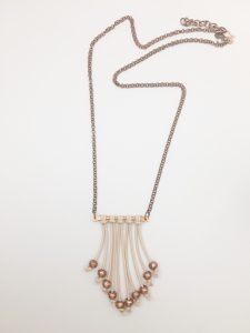 Copper and cream beaded necklace on white background.