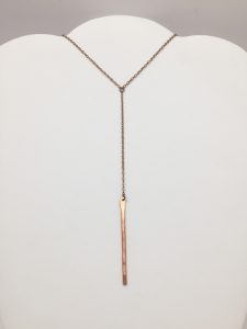 Minimalist gold vertical bar necklace on display.