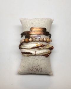 Stacked copper bracelets on pillow cushion display.