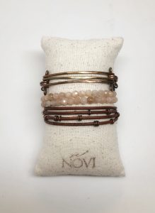 Copper and bead bracelets on a fabric cushion.