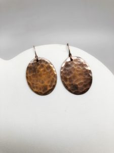 Handmade hammered brass round earrings on display.