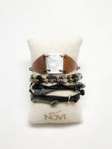 Stacked bracelets on a fabric pillow display.