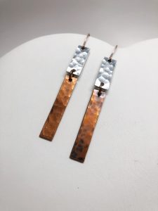 Mixed metal rectangular dangle earrings on white surface.