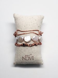 Pearl and copper bracelets on display pillow.