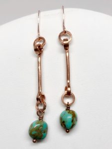 Copper earrings with turquoise beads on white background.