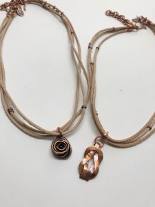 Two handcrafted bronze pendant necklaces on leather cords.