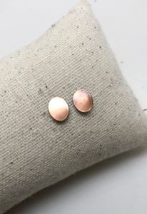 Copper stud earrings on linen pillow