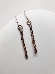 Copper twisted earrings on white background