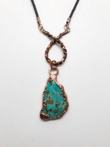 Turquoise pendant with copper details on leather cord.