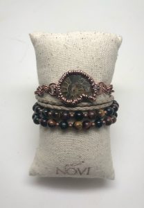 Ammonite bracelet with gemstone beads on cushion.