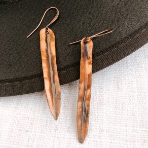 Hammered copper earrings on black background