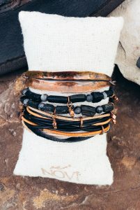 Stacked metal and leather bracelets on a cushion