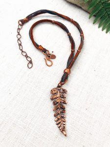Copper leaf pendant on leather necklace.
