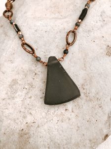 Triangle stone necklace on textured background.