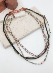 Multilayer copper chain necklace on stone background.