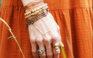 Hand wearing bracelets and rings in nature.