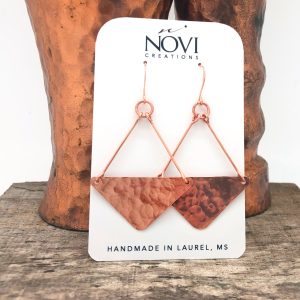 Handmade copper earrings on wooden display stand