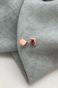 Copper square earrings on gray fabric