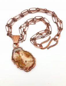 Copper chain necklace with stone pendant.
