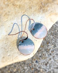 Handmade blue ceramic earrings on stone background.