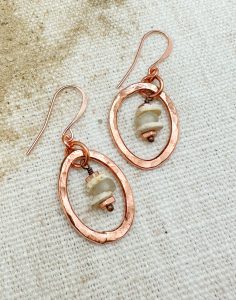 Copper earrings with beige stone beads on fabric