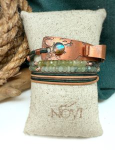 Copper and gemstone bracelet on fabric cushion.