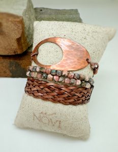 Artisan copper and beaded bracelets on woven cushion.