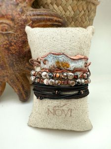 Handcrafted bracelets on burlap cushion display.
