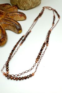 Handcrafted copper and stone necklace on white background.