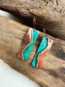 Copper and turquoise earrings on wooden background.