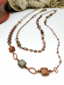 Copper jewelry with colorful stone beads on table.